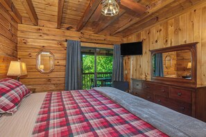 Een houten kamer met een bed, een dressoir, een televisie en uitzicht op groen.
