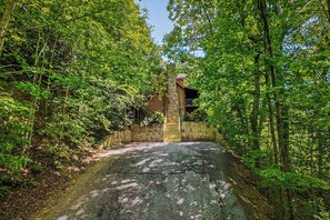 Ein steiniger Weg führt zu einem rustikalen Holzhaus, umgeben von dichtem Grün.