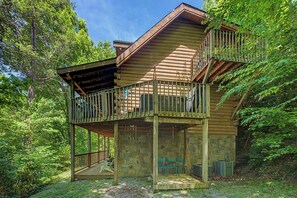 Eine Holzhütte mit Balkon, Steinmauern und einer Terrasse.