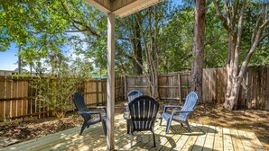 A wooden deck with Adirondack chairs, a pergola, and a wooden fence.