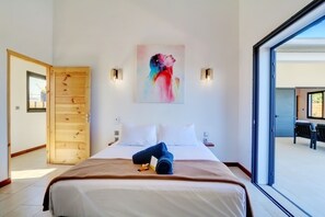 Une chambre d’hôtel avec un lit, un tableau au mur et une vue à travers une porte vitrée.
