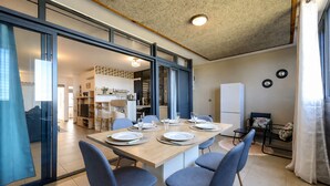 A modern kitchen with a dining area, a refrigerator, and a view into the living room.
