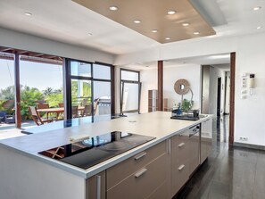 Cocina moderna con una isla grande, electrodomésticos integrados y vistas a un patio exterior.