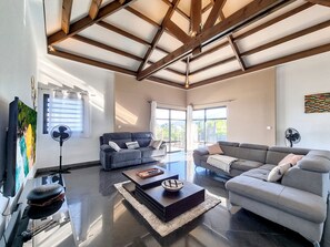 Un salón amplio con techo alto, ventanas grandes y muebles modernos.