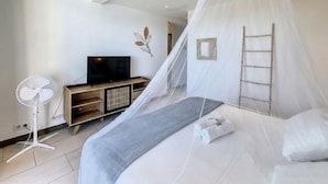 A bedroom with a bed, a TV, a fan, and a ladder.