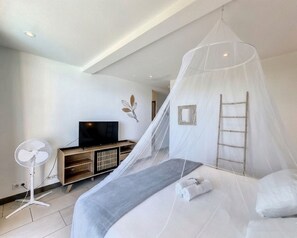 Un dormitorio con cama, televisor, ventilador y una escalera.