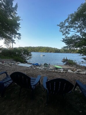A lakeside view with chairs and boats. - Sebago Lake Waterfront Cottage Sandy Beach Boats Frye Island Maine Ferry Tale (Frye Island)