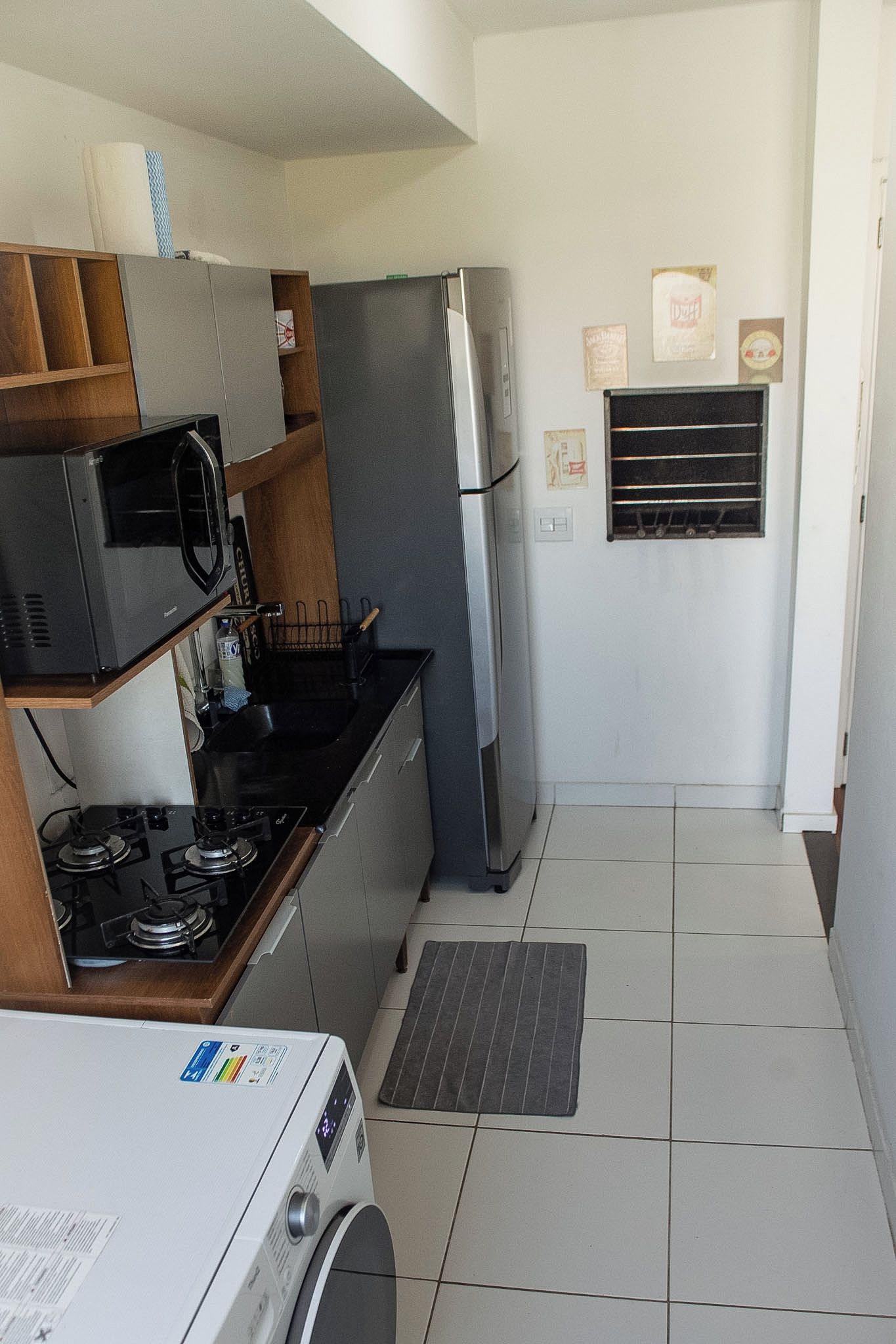 A compact kitchen with a gas stove, microwave, refrigerator, and a washing machine.