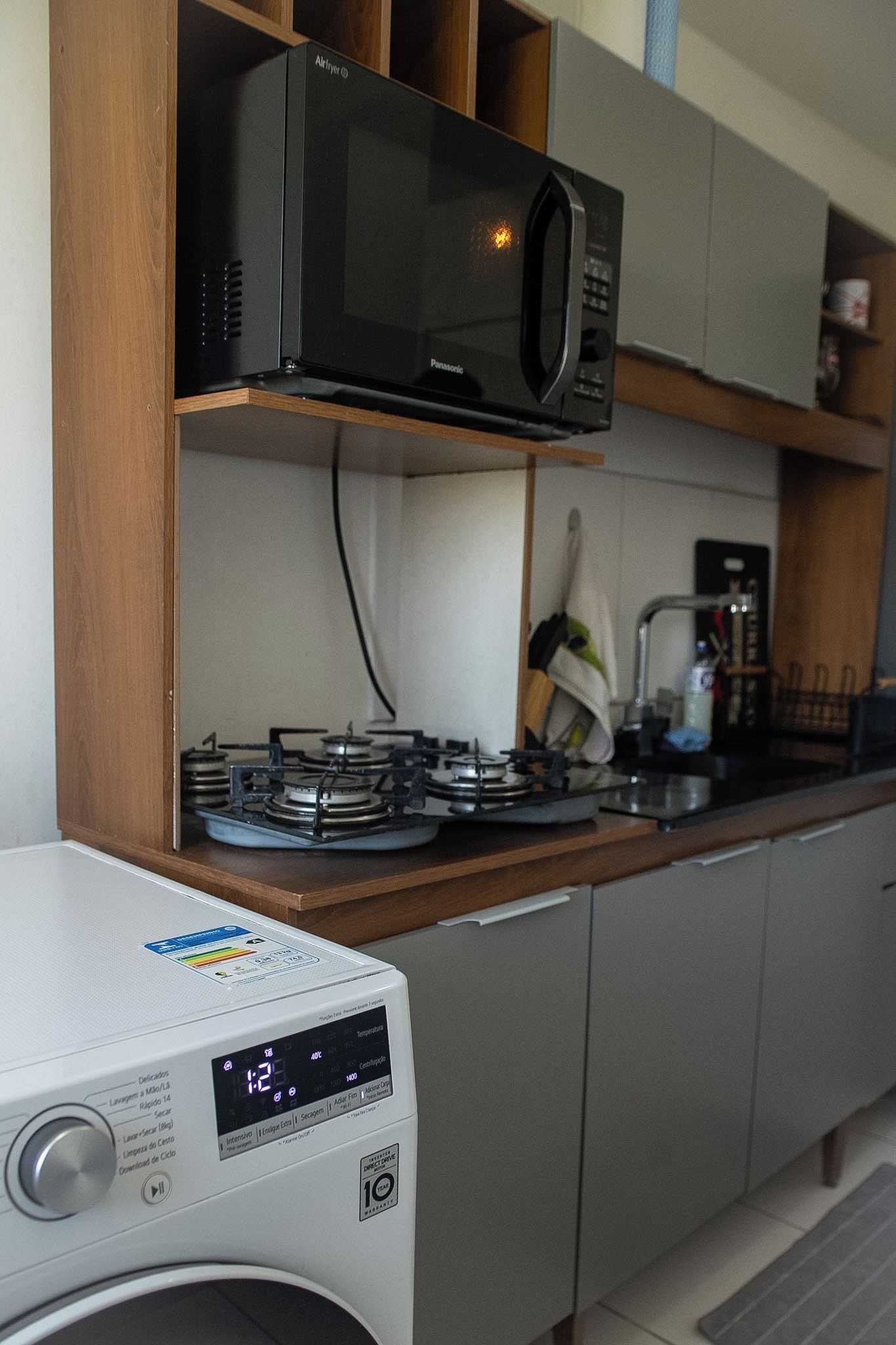 A compact kitchen with a microwave, a washing machine, and a coffee maker.