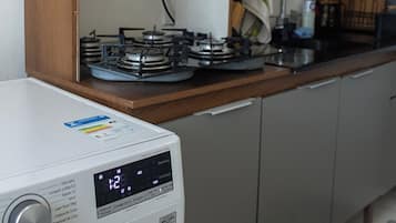 A compact kitchen with a microwave, a washing machine, and a coffee maker.
