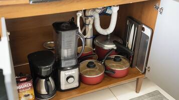 A kitchen with a coffee maker, a blender, a pot, and a can of coffee.