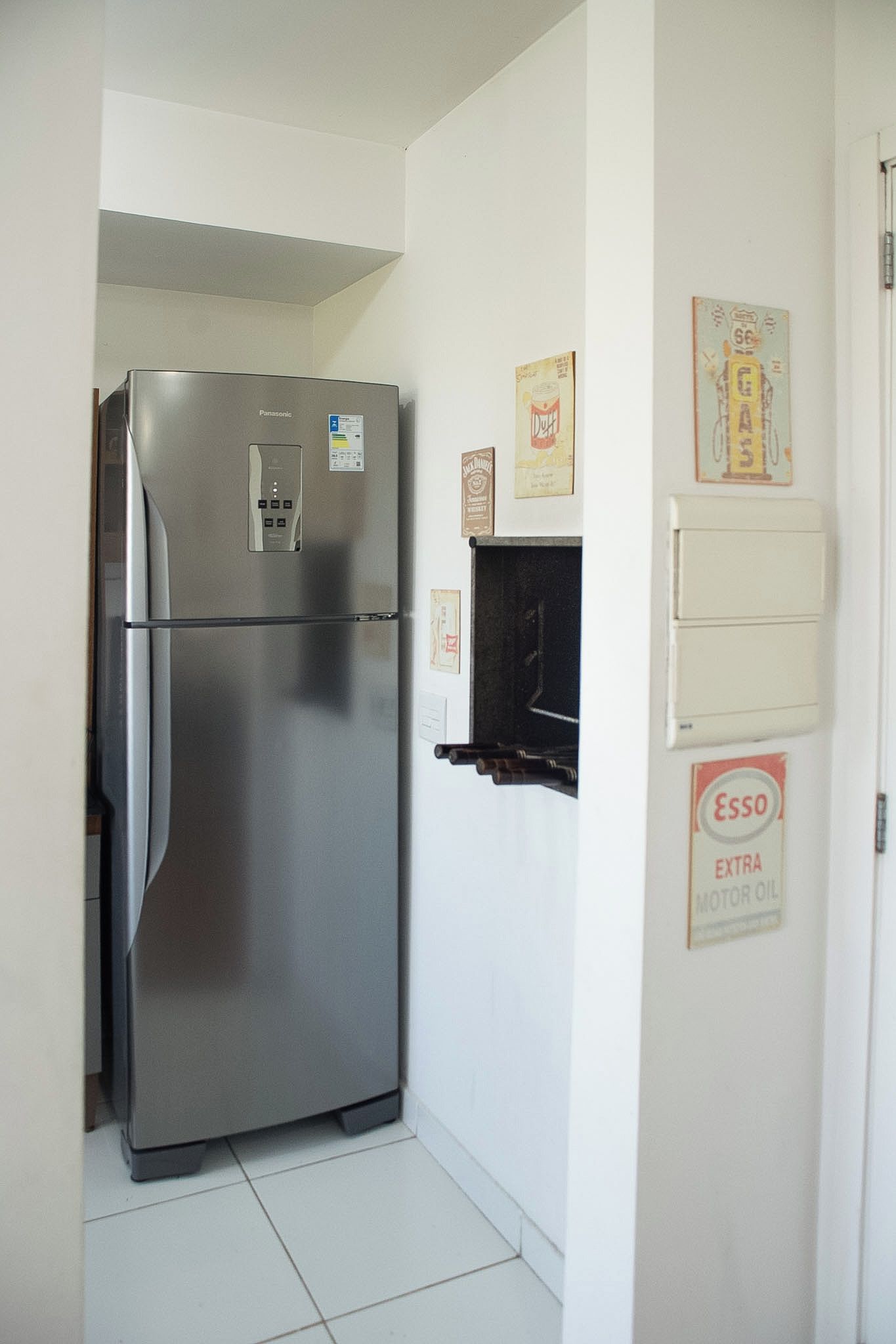 A compact kitchen with a stainless steel refrigerator, a small black appliance, and a wall-mounted electrical outlet.