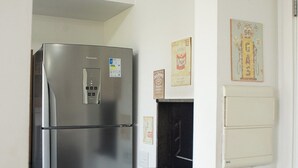 A compact kitchen with a stainless steel refrigerator, a small black appliance, and a wall-mounted electrical outlet. - Tricolor Area! Cozy apartment next to Grêmio Arena, near the airport. (Porto Alegre)