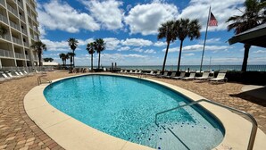 A swimming pool with lounge chairs, palm trees, and a view of the ocean. - Windward Pointe 3 Bed 2 Bath - Sleeps 10.  Free Daily Activities! (Orange Beach)
