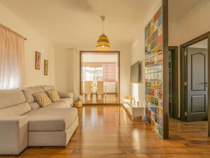 Ein Wohnzimmer mit einer Couch, einem Fernseher und einer Glaswand mit bunten Mustern.