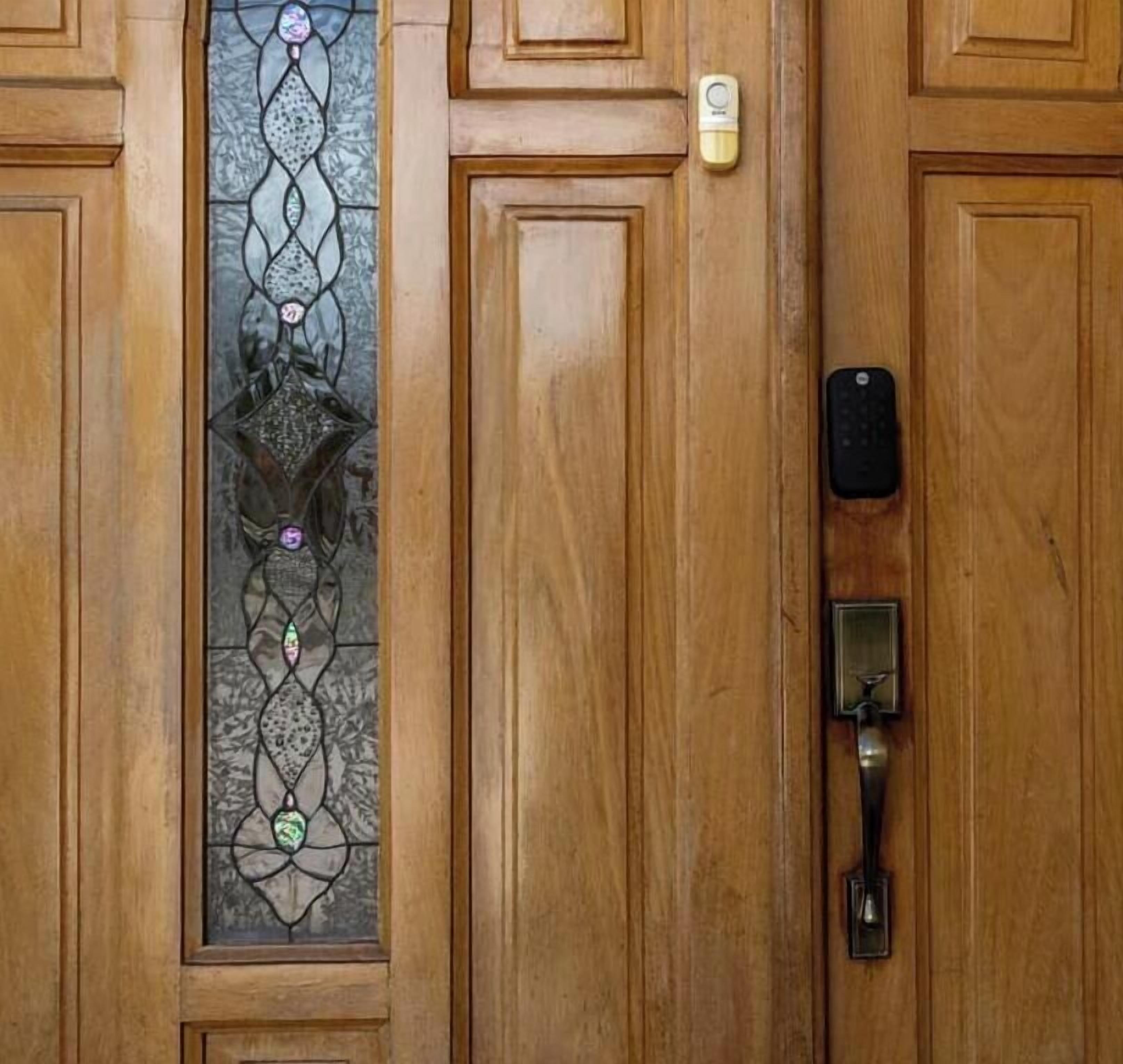 A wooden door with a glass panel, a keypad lock, and a doorbell.