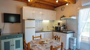 Una cocina compacta con armarios blancos, un lavamanos, un microondas y una mesa de comedor con sillas.
