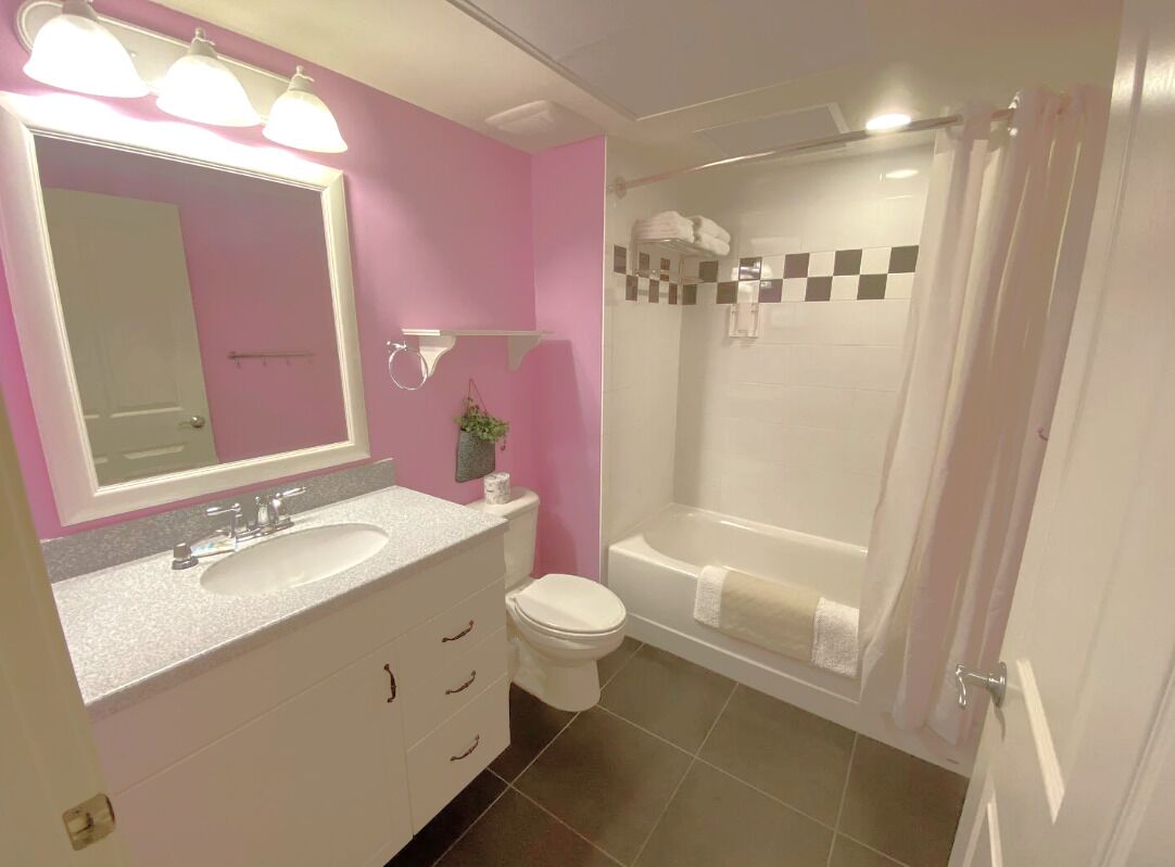A bathroom with a sink, mirror, toilet, and bathtub.