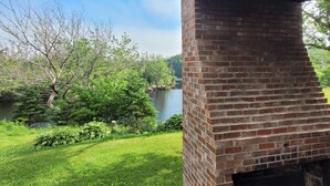 A brick fireplace with a chimney, a grassy yard, and a lake in the background. - Two-Double Bedded Motel Room at Liscombe Resort (Liscomb)