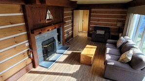 A log cabin interior with a fireplace, sofa, and wooden flooring. - Two-Double Bedded Motel Room at Liscombe Resort (Liscomb)