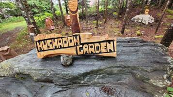 Un letrero de madera sobre una roca que dice 'Mushroom Garden' en un área boscosa.
