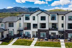 A modern multi-story residential building with a flat roof, large windows, and a well-maintained lawn. - Roam Retreat Near Snowbasin R5931 | Pool | Hot Tub (Mountain Green)