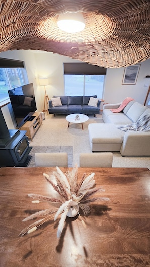 Een woonkamer met een bank, een salontafel, een televisie en een open haard.