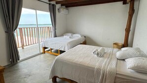 Una habitació amb dues lliteres, un balcó i vista al mar.