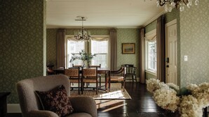 Une pièce comprenant une table à manger, des chaises, un lustre et une porte.