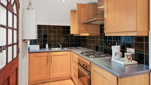 Eine Küche mit Holzausstattung, einem Gasherd, einem Spülbecken und einem Fenster mit satiniertem Glas.