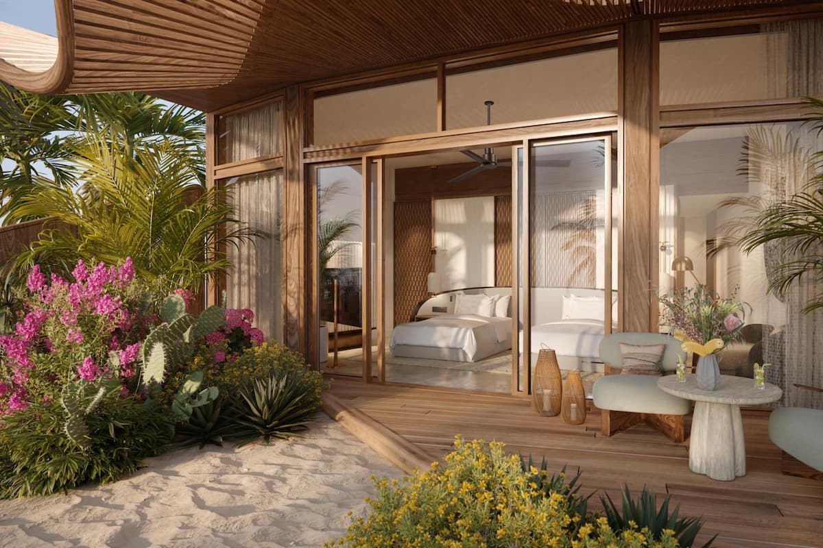 A modern bedroom with a large bed, a sitting area with a table and chairs, and a view of the outdoors.