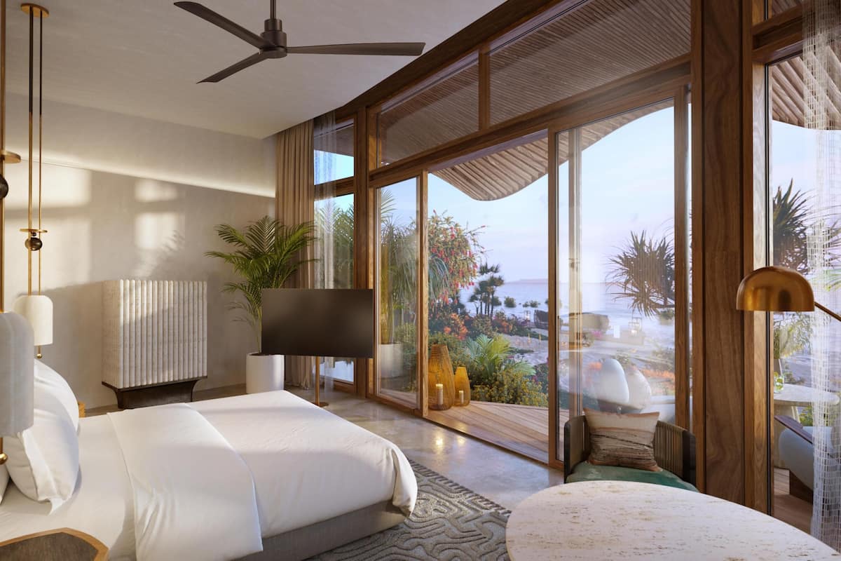 A modern bedroom with a bed, a TV, a ceiling fan, and large windows overlooking a garden.