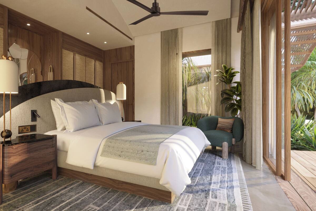 A bedroom with a bed, nightstands, a ceiling fan, a chair, and a view of greenery.