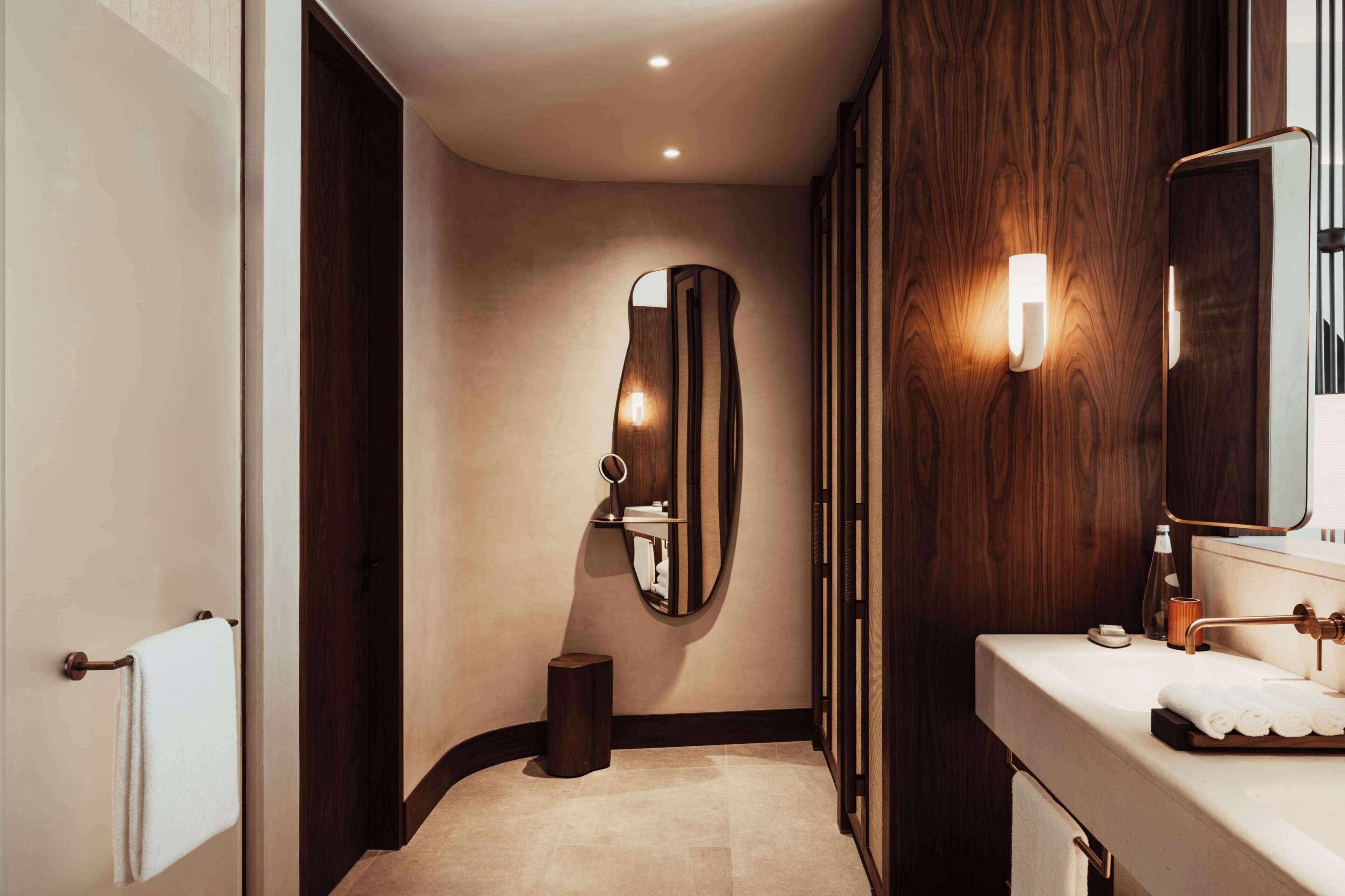 Une salle de bain moderne avec un meuble-lavabo en bois, un grand miroir et un porte-serviettes.