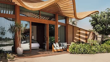 Una casa moderna con amplios ventanales, una estructura de madera curva, un sofá y una planta en maceta.