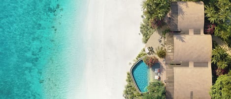 Un resort con piscina, playa y abundante vegetación.