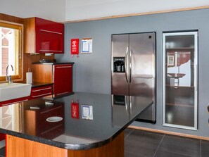 A modern kitchen with a stainless steel refrigerator, wooden cabinets, and a black countertop.