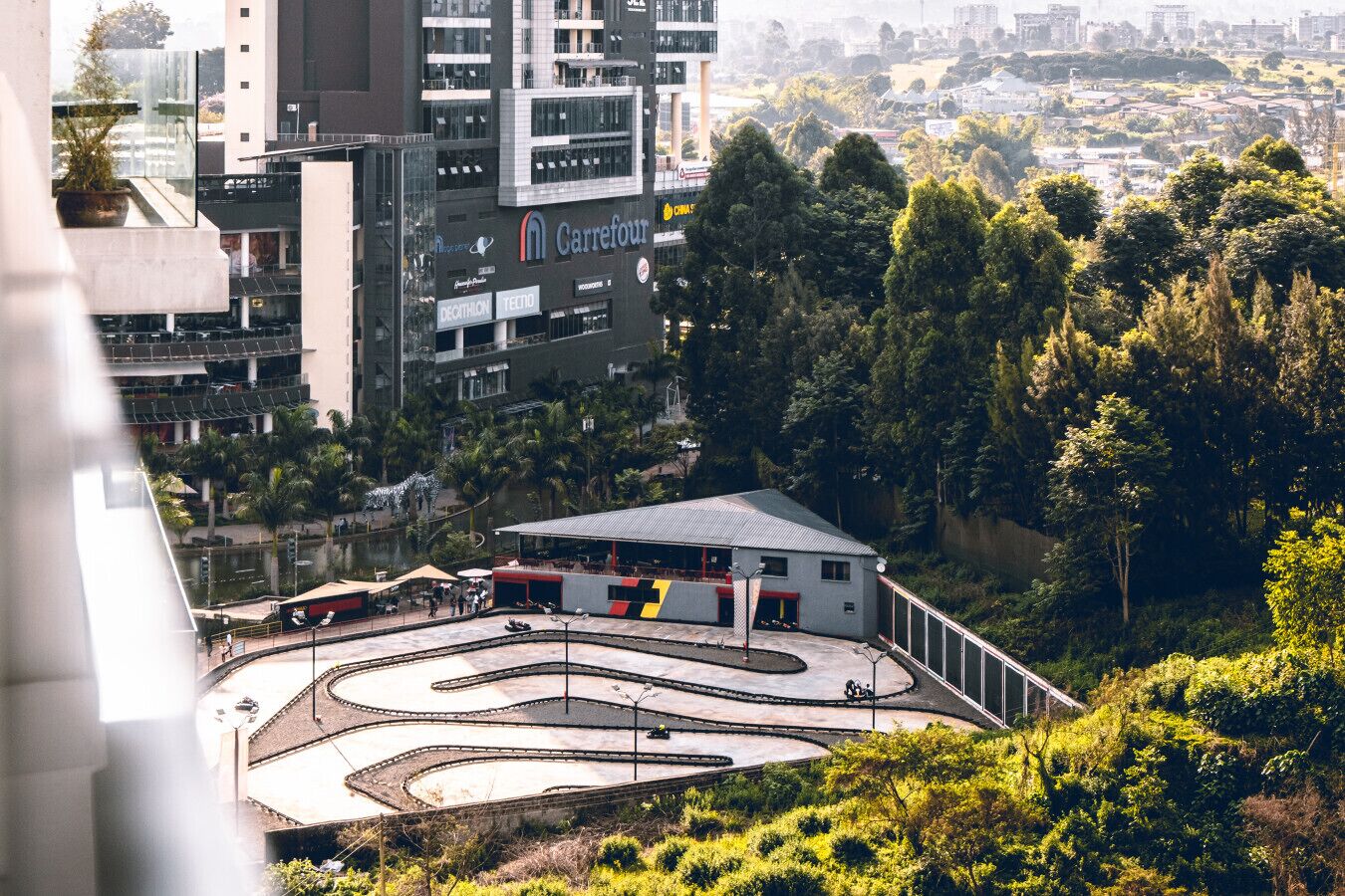 A view of a cityscape with a Carrefour store, a building with a red and white facade, and a winding road.