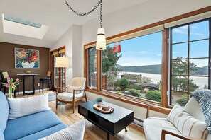 Un salon moderne avec une grande fenêtre, un canapé, une table basse et un fauteuil.