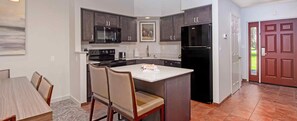 A kitchen with dark cabinets, a black refrigerator, a microwave, and a dining area with chairs and a table. - Eagle Crest Resort 3 Bedroom Condo with view of Golf Course (Redmond)