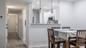 A modern kitchen with white cabinets, a dining table with chairs, and pendant lighting. - Spacious newly renovated and furnished 3-bedroom condo in beautiful Gulf Shores (Gulf Shores)