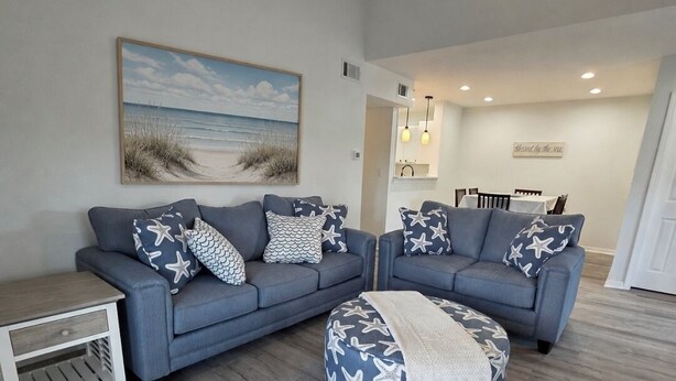 A living room with two sofas, a coffee table, and a side table. There is a painting on the wall and a ceiling fan. - Spacious newly renovated and furnished 3-bedroom condo in beautiful Gulf Shores (Gulf Shores)