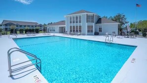 A swimming pool with a clear blue water, surrounded by a white deck, and a building with large windows in the background. - Spacious newly renovated and furnished 3-bedroom condo in beautiful Gulf Shores (Gulf Shores)