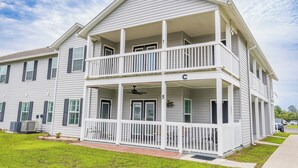 A two-story building with a balcony, a covered porch, and a small garden area. - Spacious newly renovated and furnished 3-bedroom condo in beautiful Gulf Shores (Gulf Shores)
