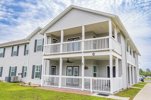 A two-story building with a balcony, a covered porch, and a small garden area.