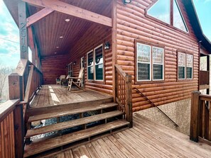 Eine Holzhütte mit Veranda, Treppe und Blick auf die umliegende Landschaft.