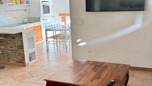 Una sala de estar con un sofá, una mesa de centro de madera y un televisor de pantalla plana montado en la pared.