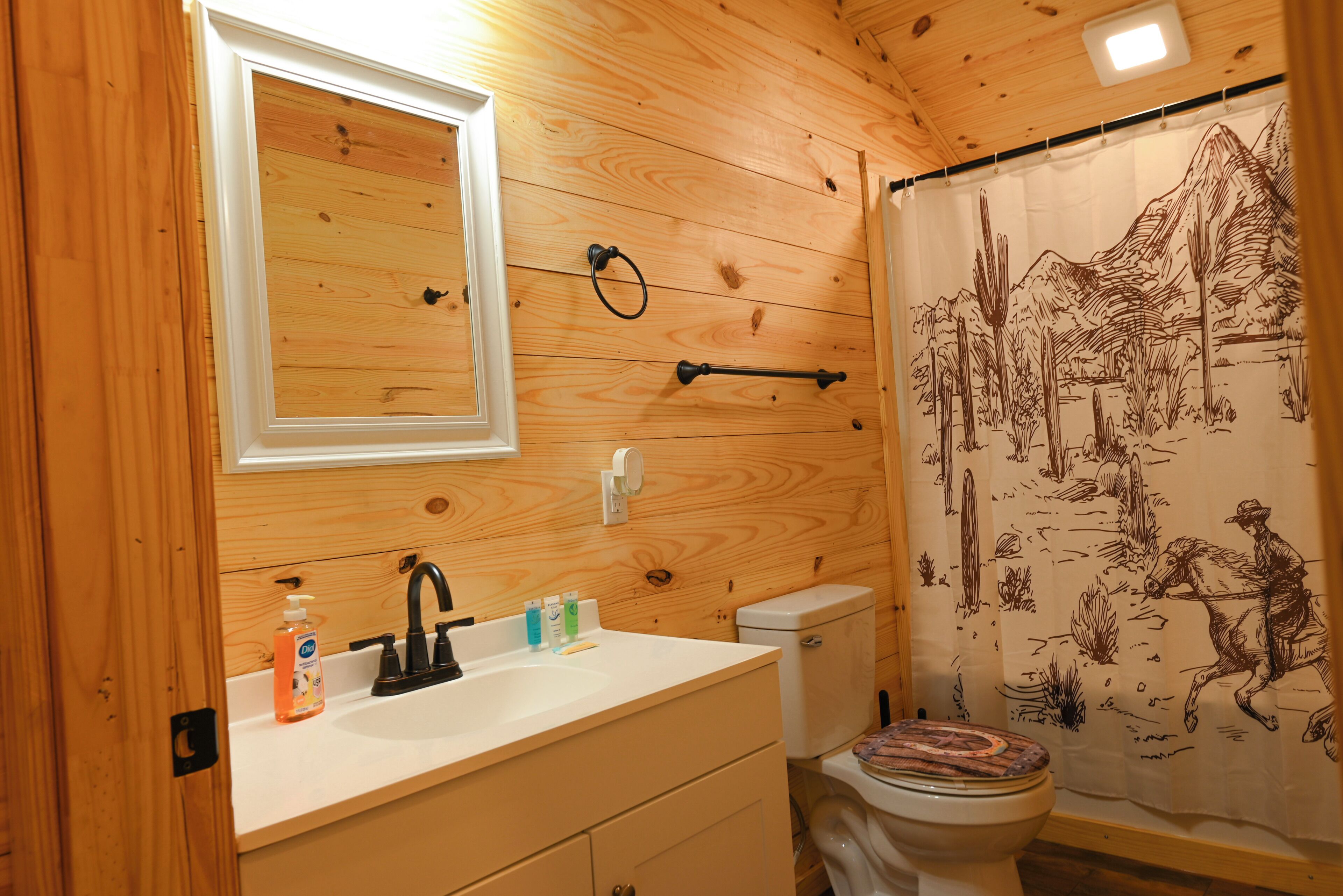 Een badkamer met houten lambrisering, een wastafel, spiegel, toilet en douchegordijn.
