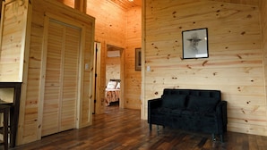 Un interno in legno con un divano nero, pareti in legno e un quadro appeso al muro.