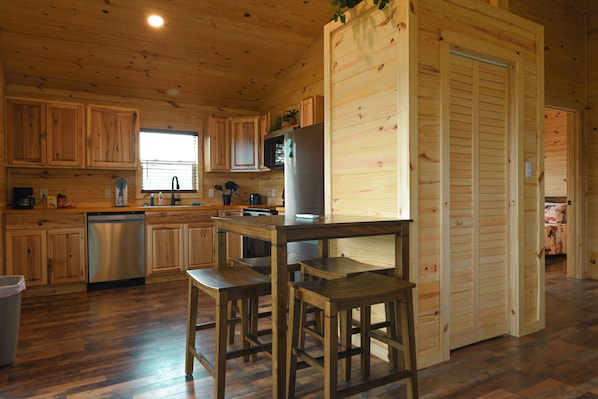 A wooden cabin interior with a kitchen, wooden dining table, and chairs.